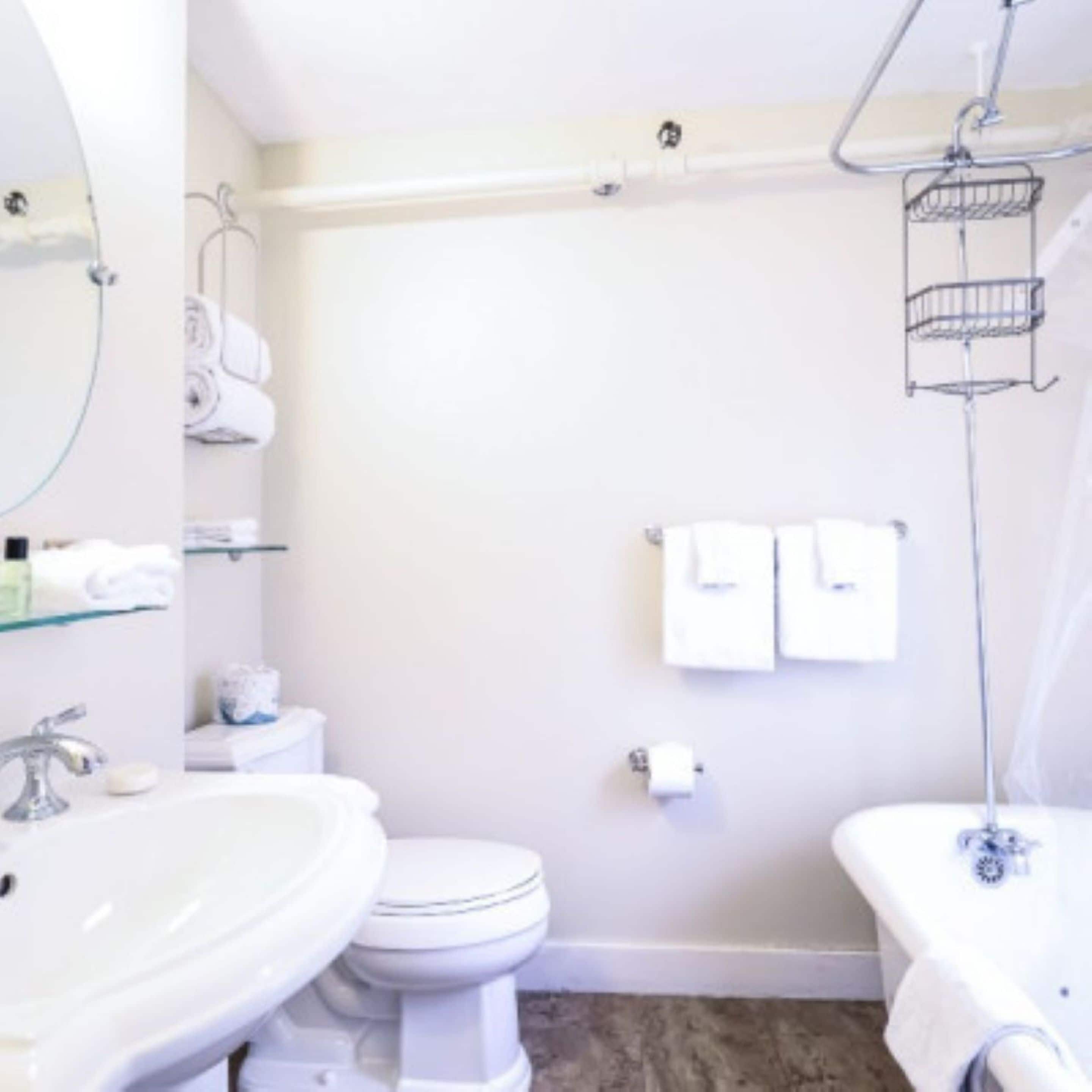 A bathroom with a sink, toilet, and bathtub. There are towels and toiletries on the wall.
