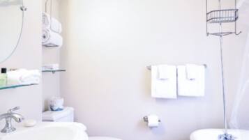 A bathroom with a sink, toilet, and bathtub. There are towels and toiletries on the wall.