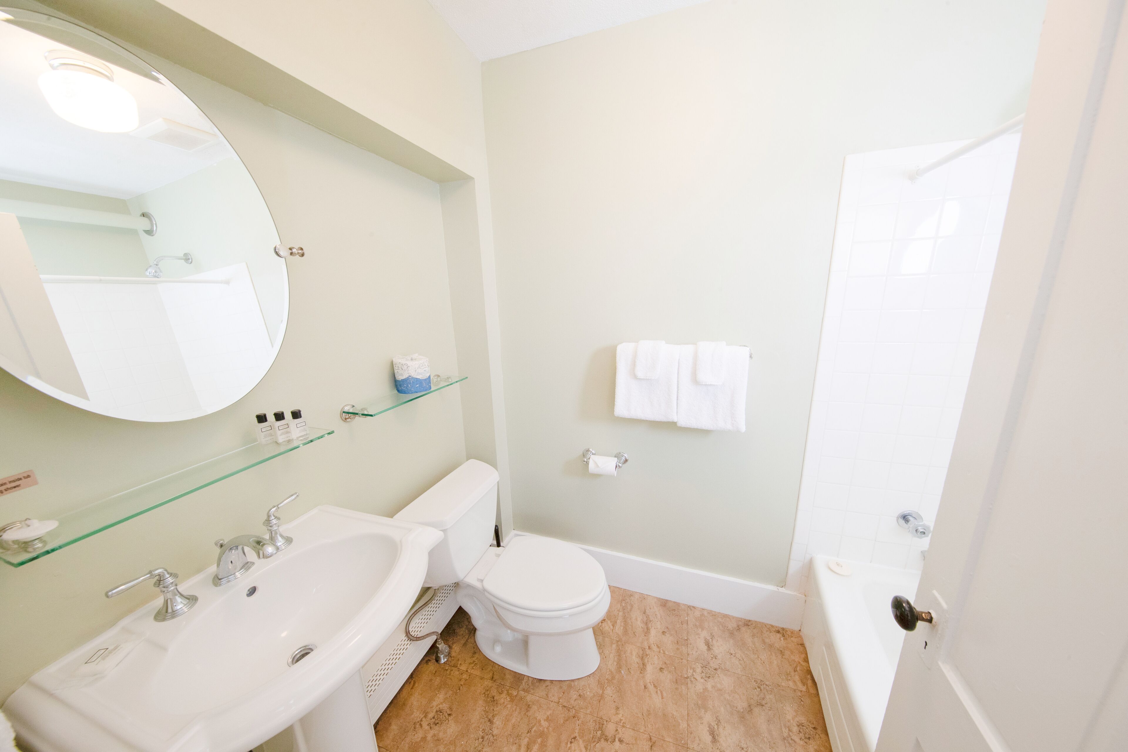 A bathroom with a sink, toilet, and bathtub. There is a mirror above the sink and a towel rack on the wall.