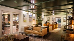 A spacious living room with a large sofa, a coffee table, and a fireplace. There are multiple seating areas and a dining table. - The New London Inn (New London)