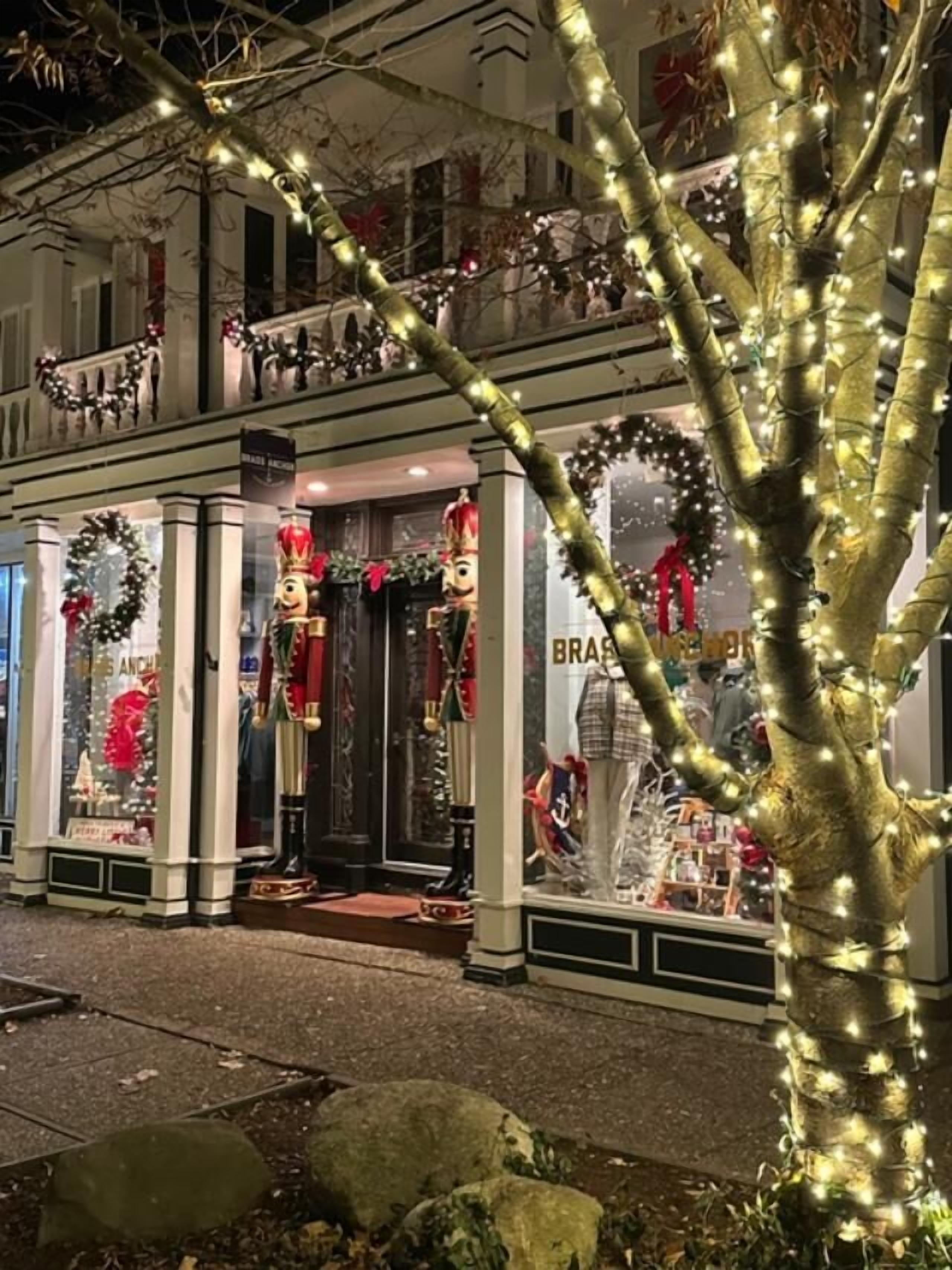 A building with a storefront decorated with Christmas lights and wreaths.