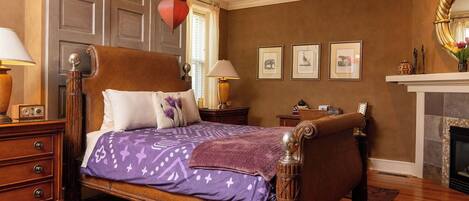 Une chambre à coucher de style traditionnel, avec un grand lit, une tête de lit en bois et une cheminée.
