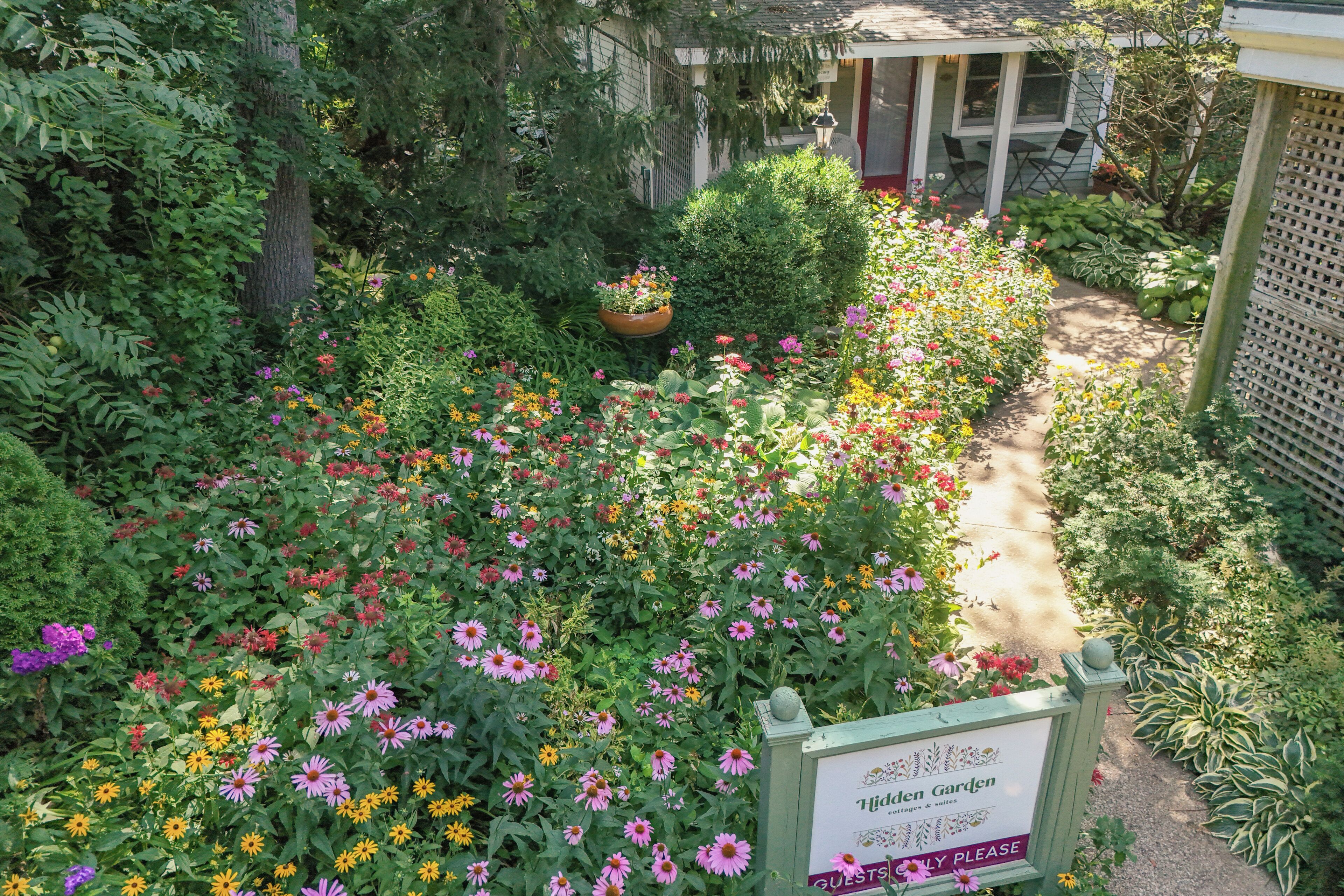 A garden with a sign that reads 'Hidden Garden cottages & suites' and a pathway.