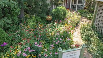 A garden with a sign that reads 'Hidden Garden cottages & suites' and a pathway.