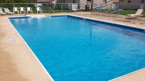 A rectangular swimming pool with clear blue water, surrounded by lounge chairs and a concrete deck. - Americas Best Value Inn Palmyra Hershey (Palmyra)