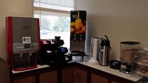 Estación de café con una máquina de café Douwe Egberts, dispensador de zumo de frutas, dispensador de leche y dispensador de cereales.