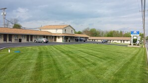 Un motel con área de estacionamiento techada, césped y un letrero que indica que es Americas Best Value Inn.