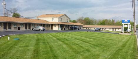 Un motel con área de estacionamiento techada, césped y un letrero que indica que es Americas Best Value Inn.