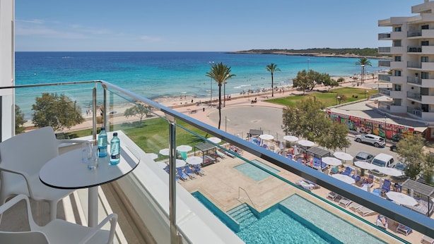 Un balcón con piscina, vista a la playa y un letrero de supermercado.