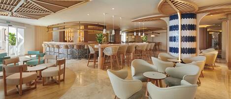 Un moderno vestíbulo de hotel con una zona de bar, espacios para sentarse y un techo decorativo de madera.