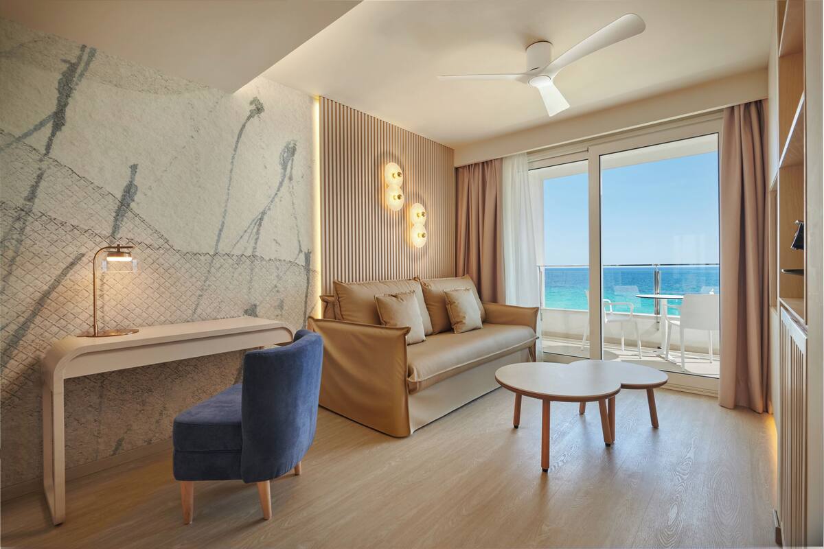 A modern room with a sofa, a desk, and a view of the ocean.