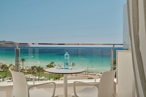A balcony with a table and chairs, overlooking a beach with clear turquoise water and a distant mountain range. - Hipotels Flamenco (Sant Llorenc des Cardassar)