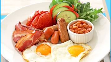 Un plato con tocino, salchichas, huevos, frijoles y verduras en rodajas.