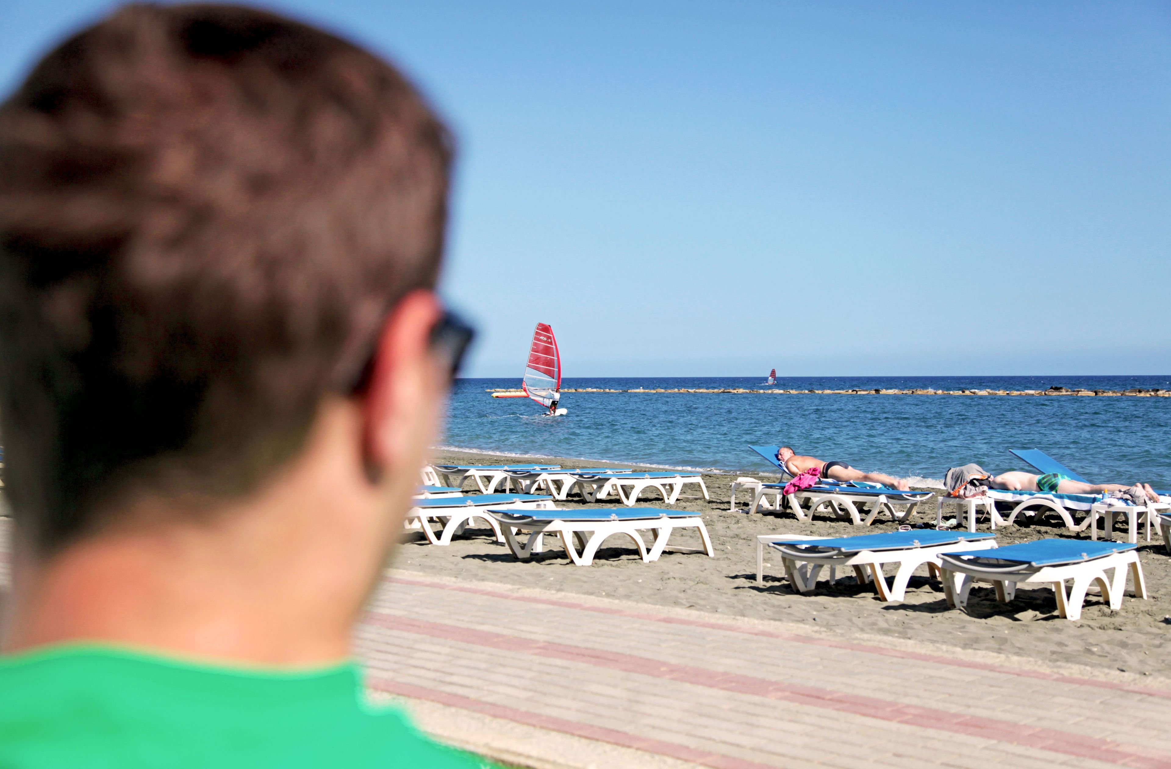 Una playa con filas de tumbonas y una persona en primer plano.