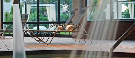 A poolside area with a lounge chair and a hot tub.