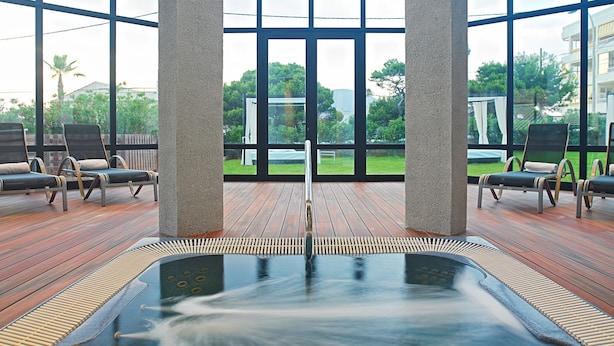 A spa area with a hot tub, wooden deck, and lounge chairs. - Protur Turó Pins Hotel (Capdepera)