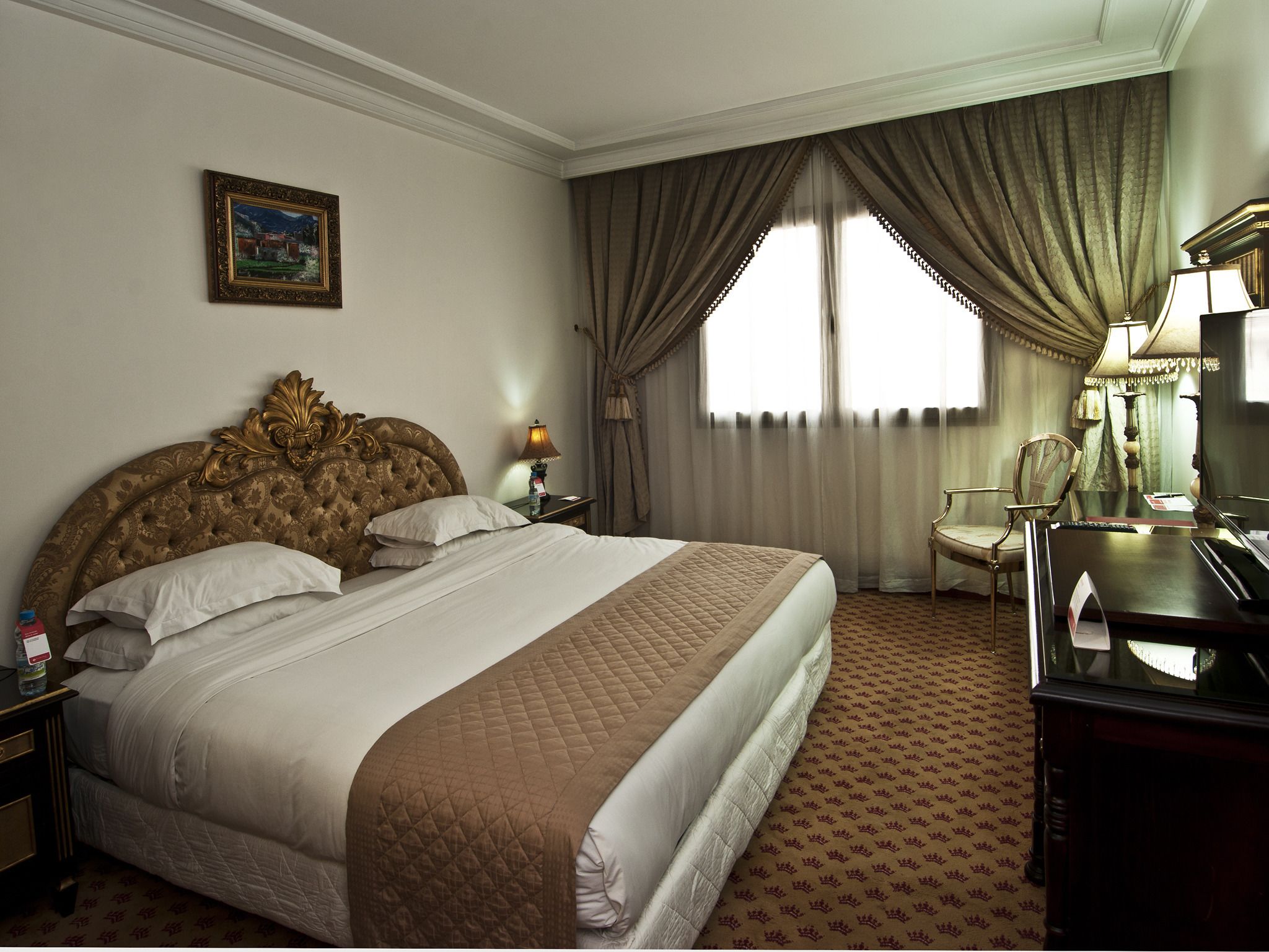 Une chambre d’hôtel avec un grand lit, une table de chevet, un bureau avec une lampe et une chaise.