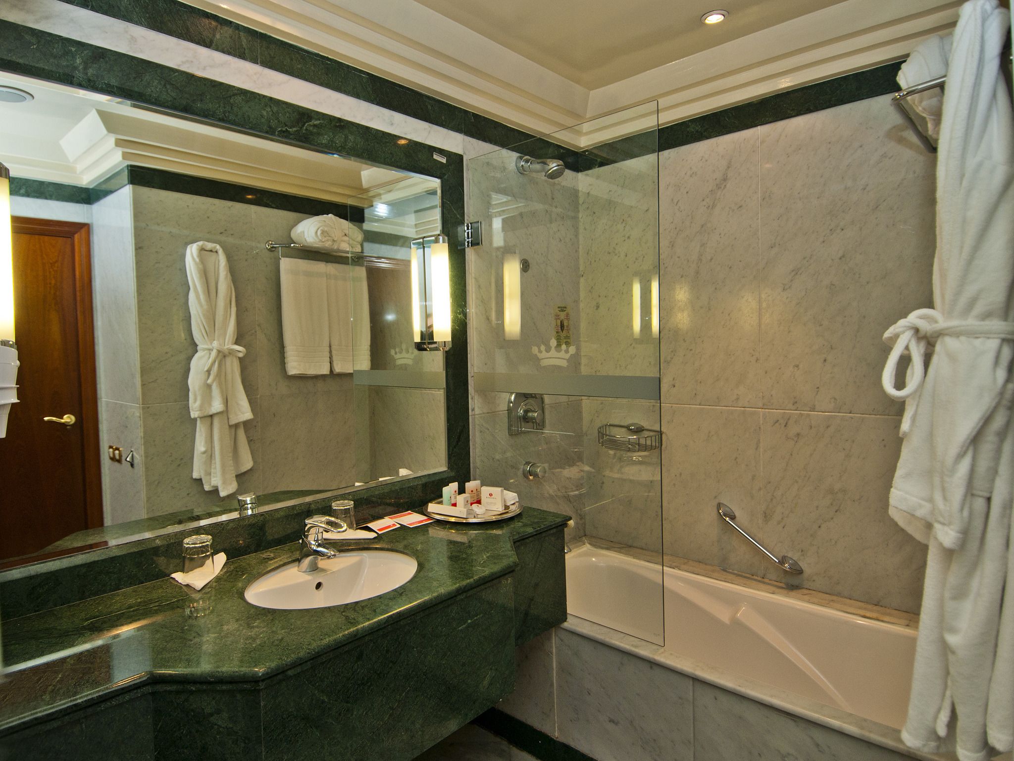 Un baño moderno con un espejo grande, un lavamanos, una bañera y una ducha con mampara de cristal.
