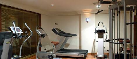 Un gimnasio con máquinas de cardio, cinta de correr y equipo de levantamiento de pesas.