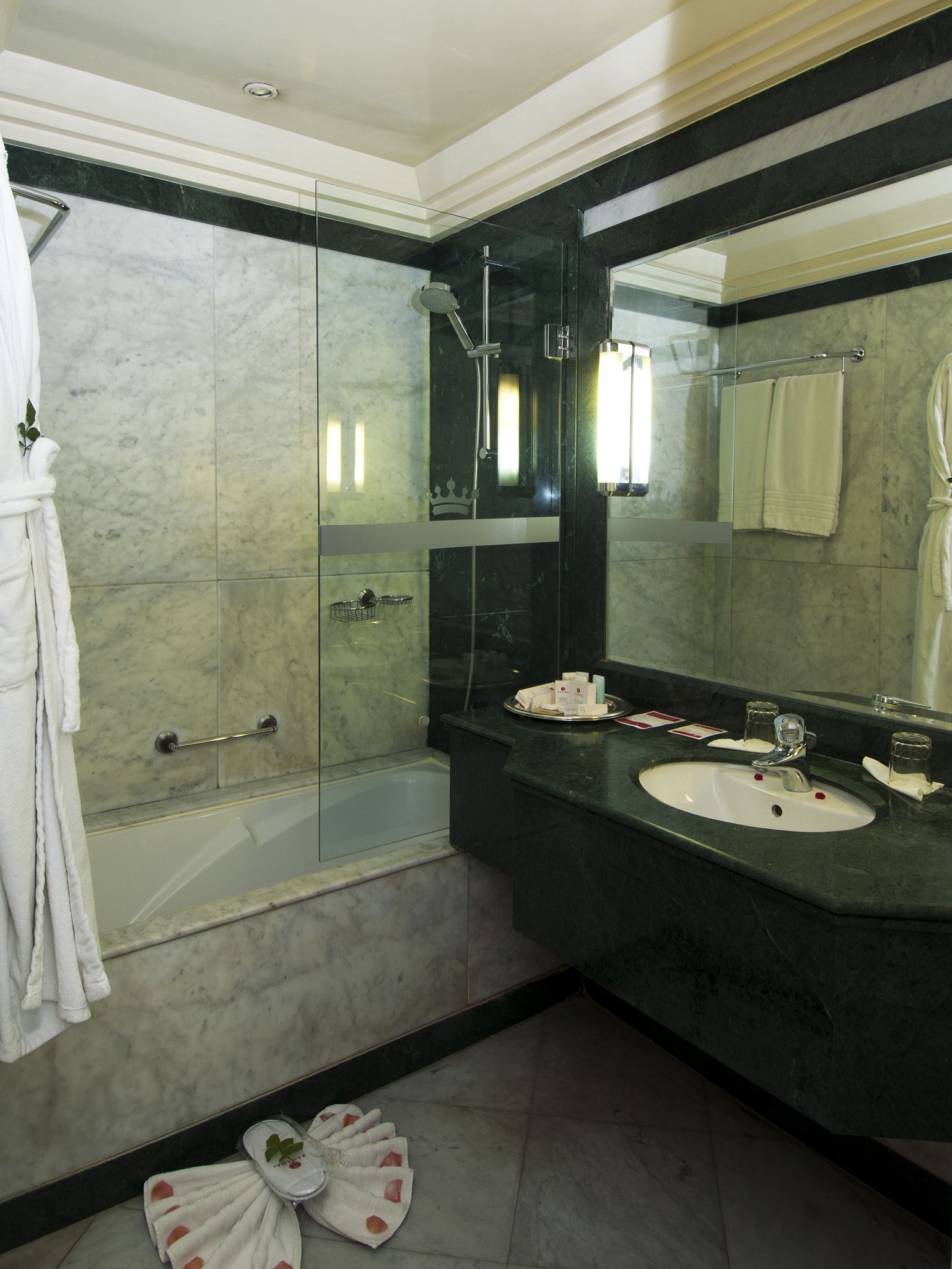 Un baño moderno con ducha de vidrio, un espejo grande y tocador con lavamanos.