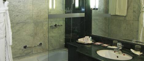 Un baño moderno con ducha de vidrio, un espejo grande y tocador con lavamanos.