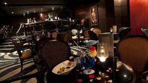 Un restaurante tenuemente iluminado con una mesa larga, sillas y una zona de bufé.