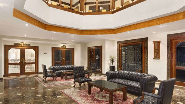 Un vestíbulo amplio con techo alto, una escalera de madera y un espejo grande y ornamentado.