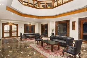 A spacious lobby with a high ceiling, a wooden staircase, and a large, ornate mirror. - Ramada by Wyndham Fes (Fes)