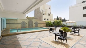 Un área de piscina al aire libre con suelo de baldosas, piscina y mobiliario exterior.