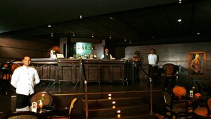 Zona de bar con mostrador, sillas y una escalera.