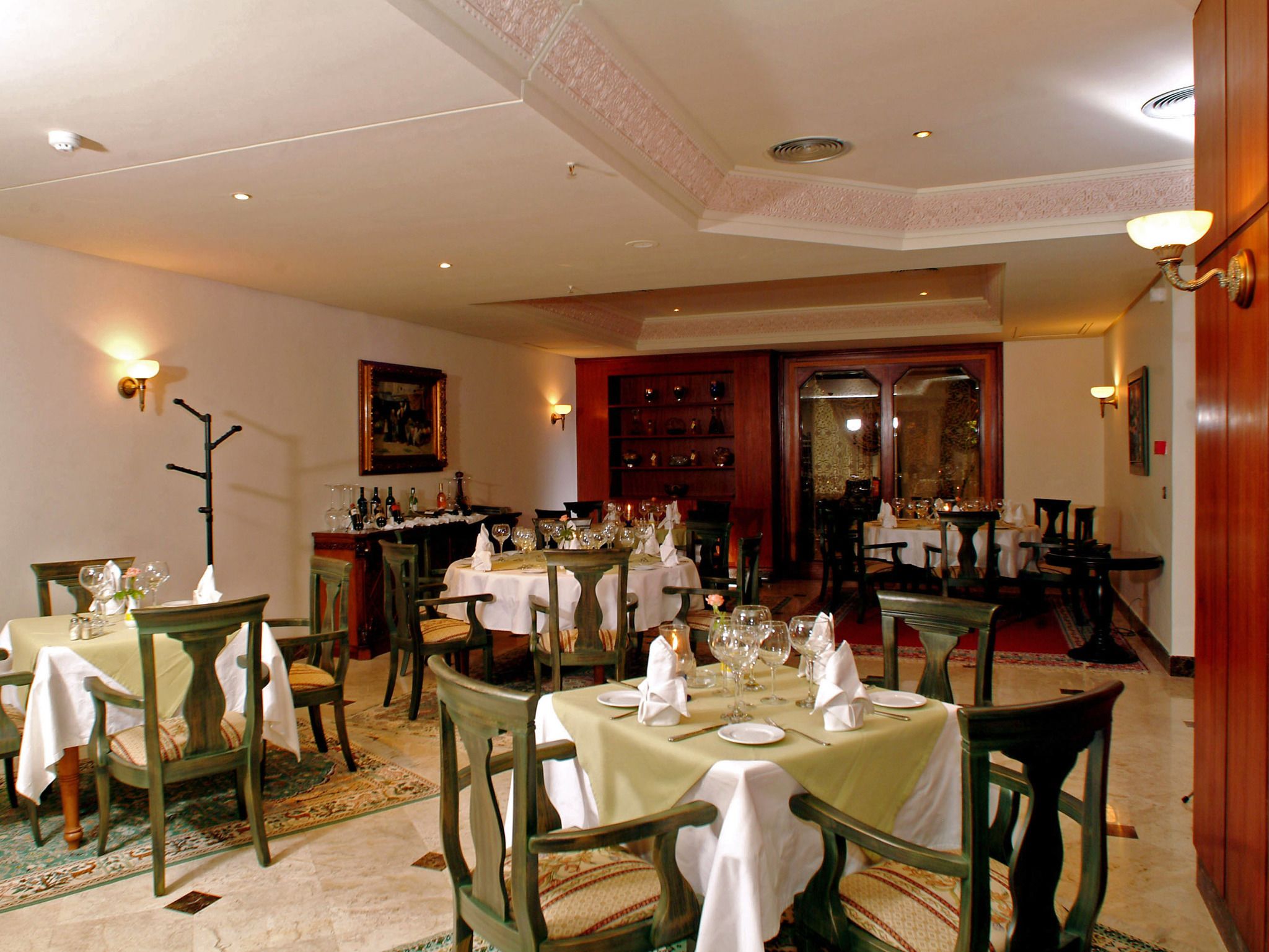 Un comedor con mesas dispuestas para varios comensales, con sillas de madera clásica y manteles blancos.