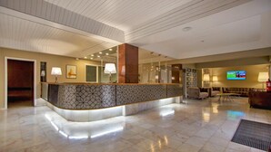 A hotel lobby with a curved reception desk, a large mirror, and a television screen. - Turial Old Town Ocean View (Albufeira)