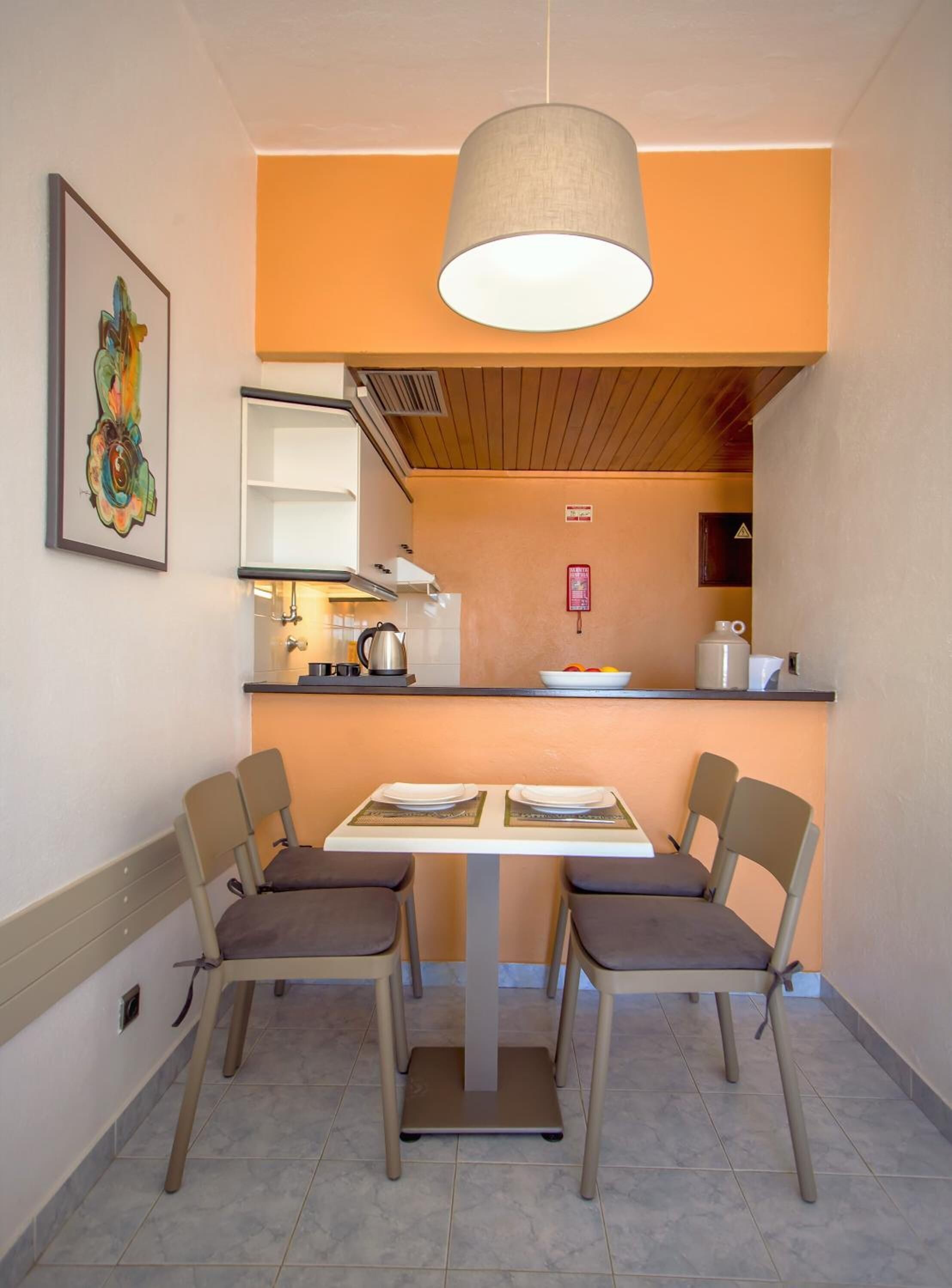A compact kitchen with a dining table set for two, equipped with chairs and a hanging light fixture.