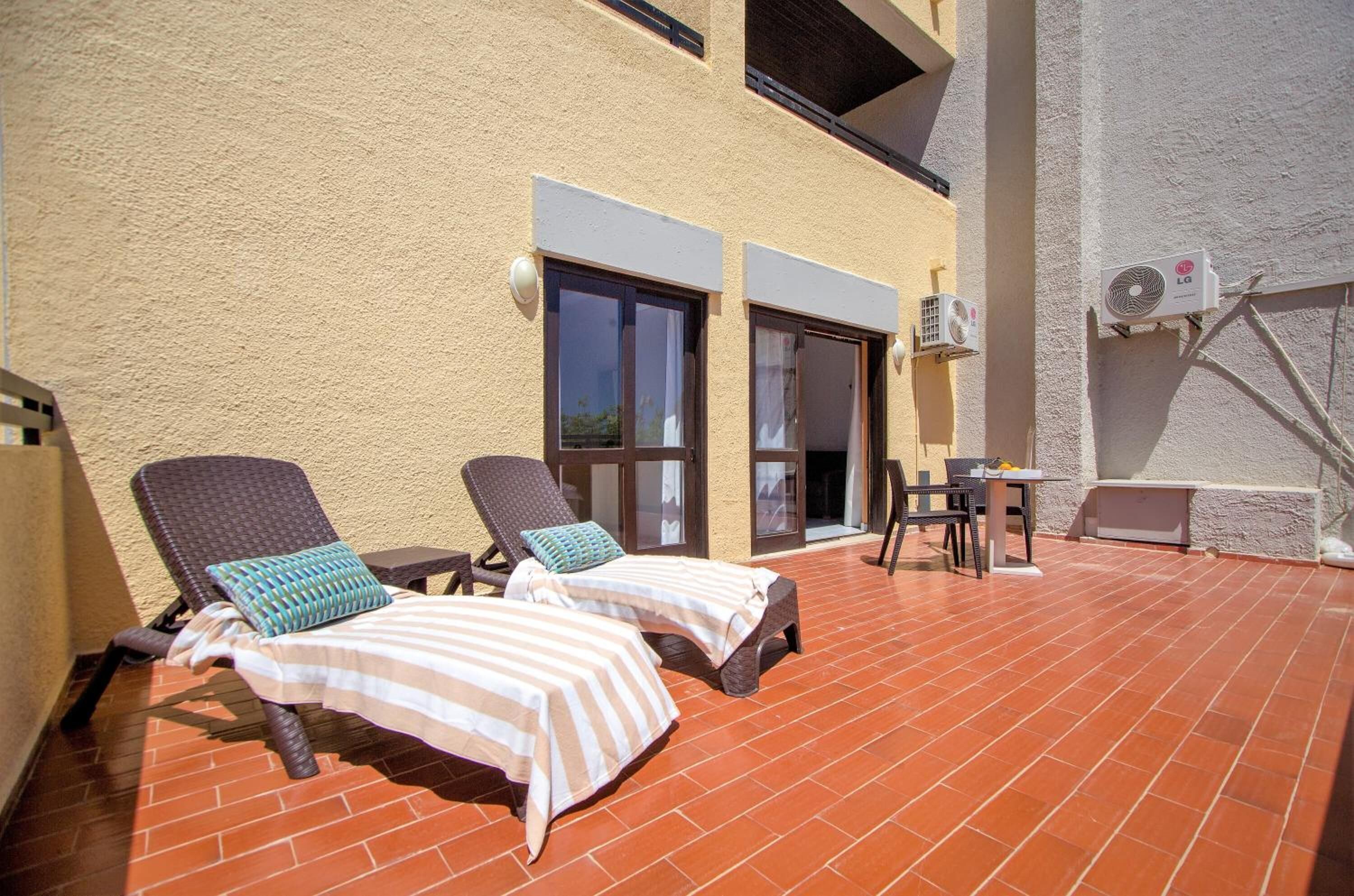 Une terrasse sur le toit équipée de deux chaises longues, d’une petite table et d’une chaise.