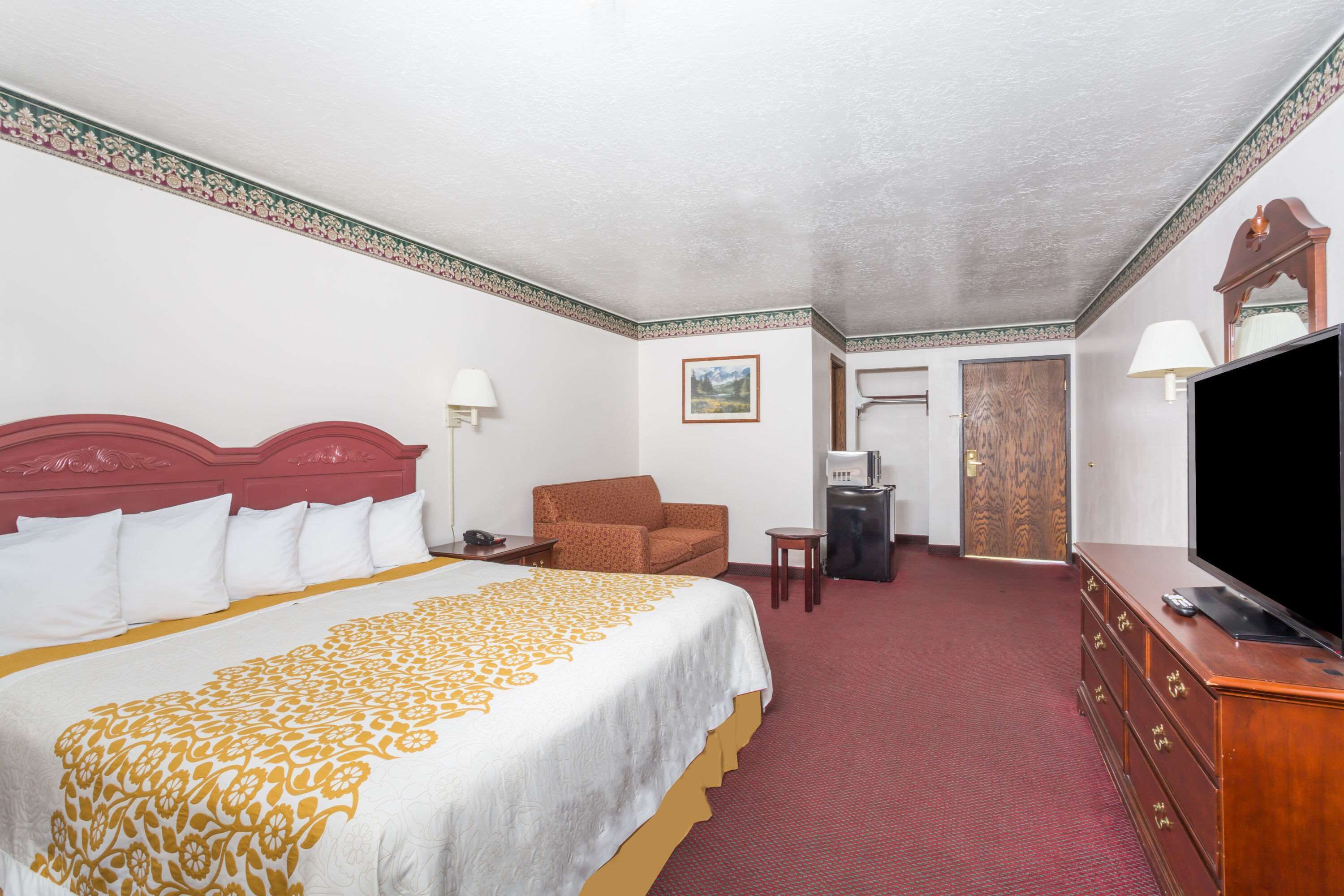A hotel room with a large bed, a television, a desk, and a chair.