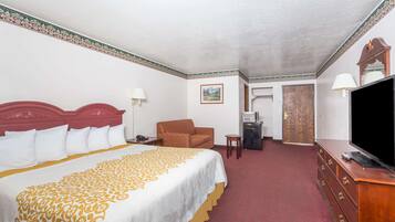 A hotel room with a large bed, a television, a desk, and a chair.