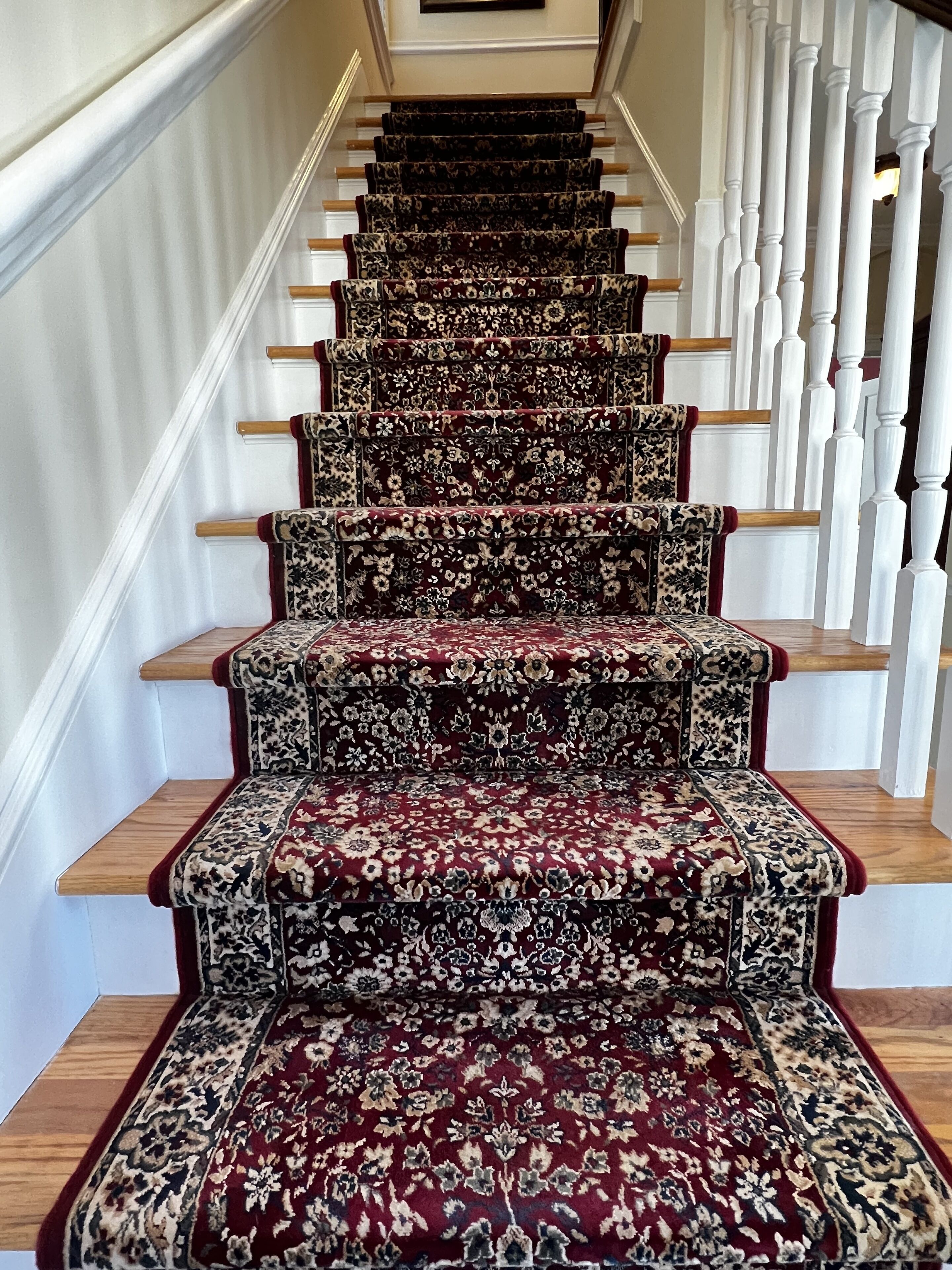 Eine Treppe mit gemustertem Teppich und Holzstufen.