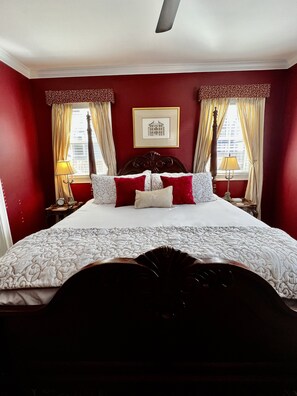 A hotel room with a large bed, red walls, and two windows with curtains. - Almondy Inn (Newport)