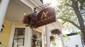 Placa para o Almondy Bed & Breakfast Inn, com um cesto de flores pendurado e um corrimão de varanda branco.
