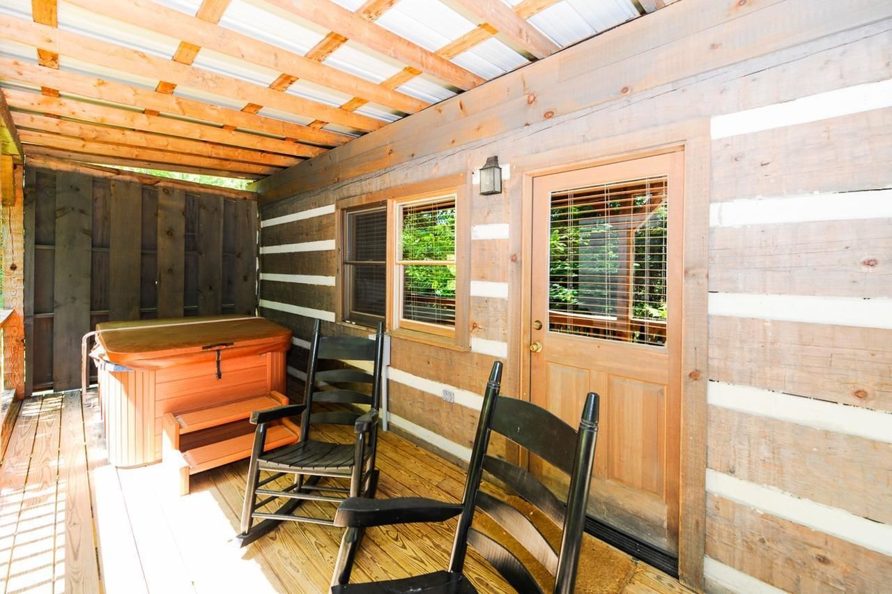 A wooden cabin with a wooden bench, a hot tub, and a door with windows.