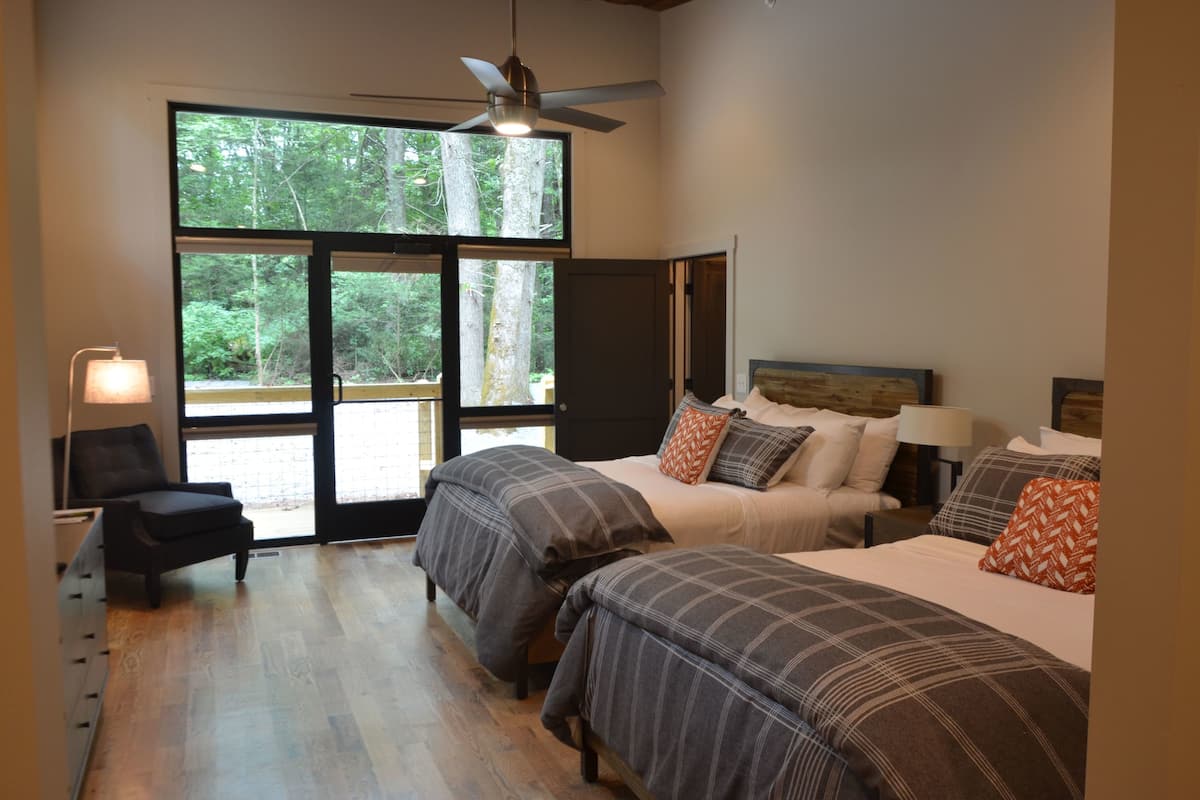 A bedroom with two beds, a chair, a desk, and a ceiling fan.