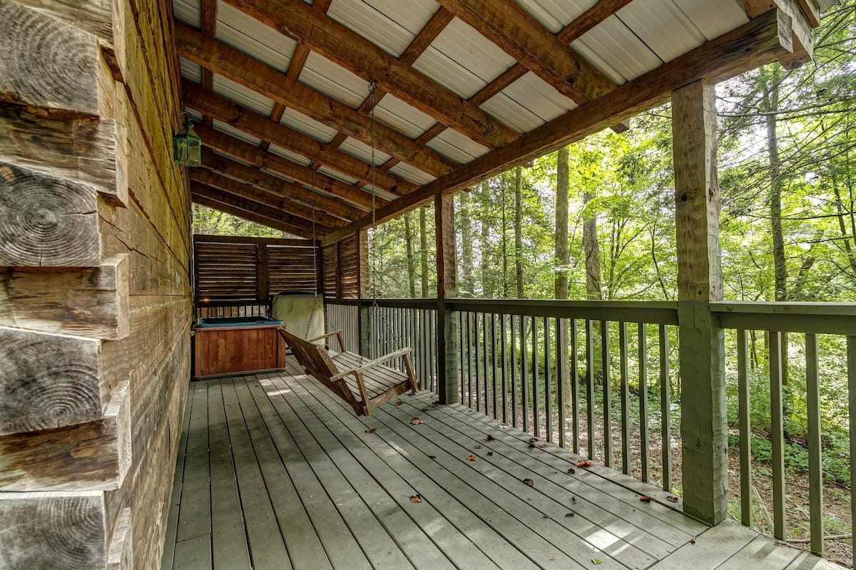 A wooden deck with a bench and a view of a forest.