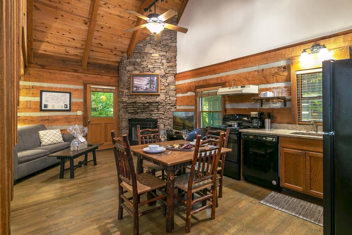 A rustic cabin interior with a dining area, kitchen, and living room.