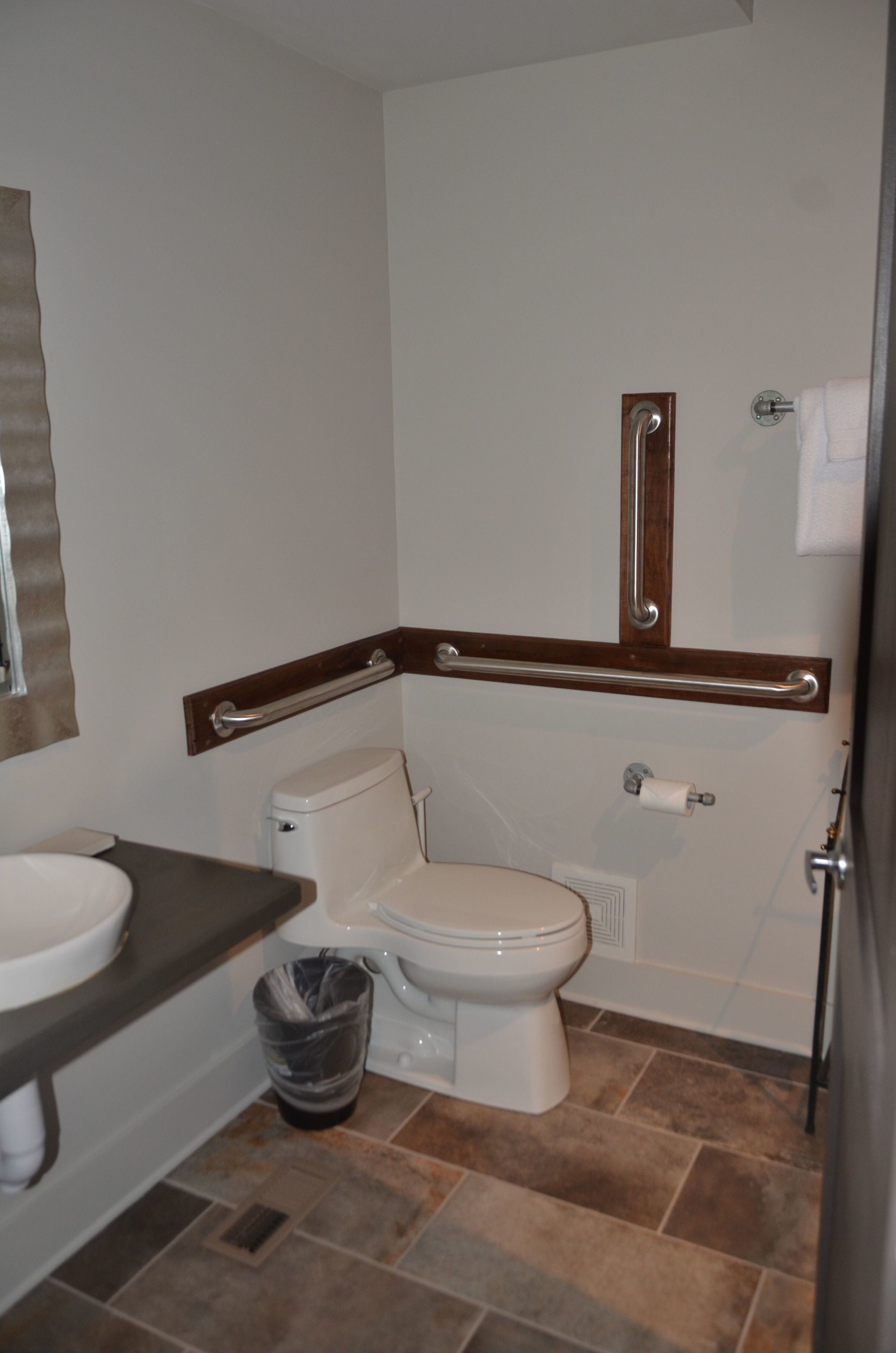 A bathroom with a toilet, sink, and grab bars.