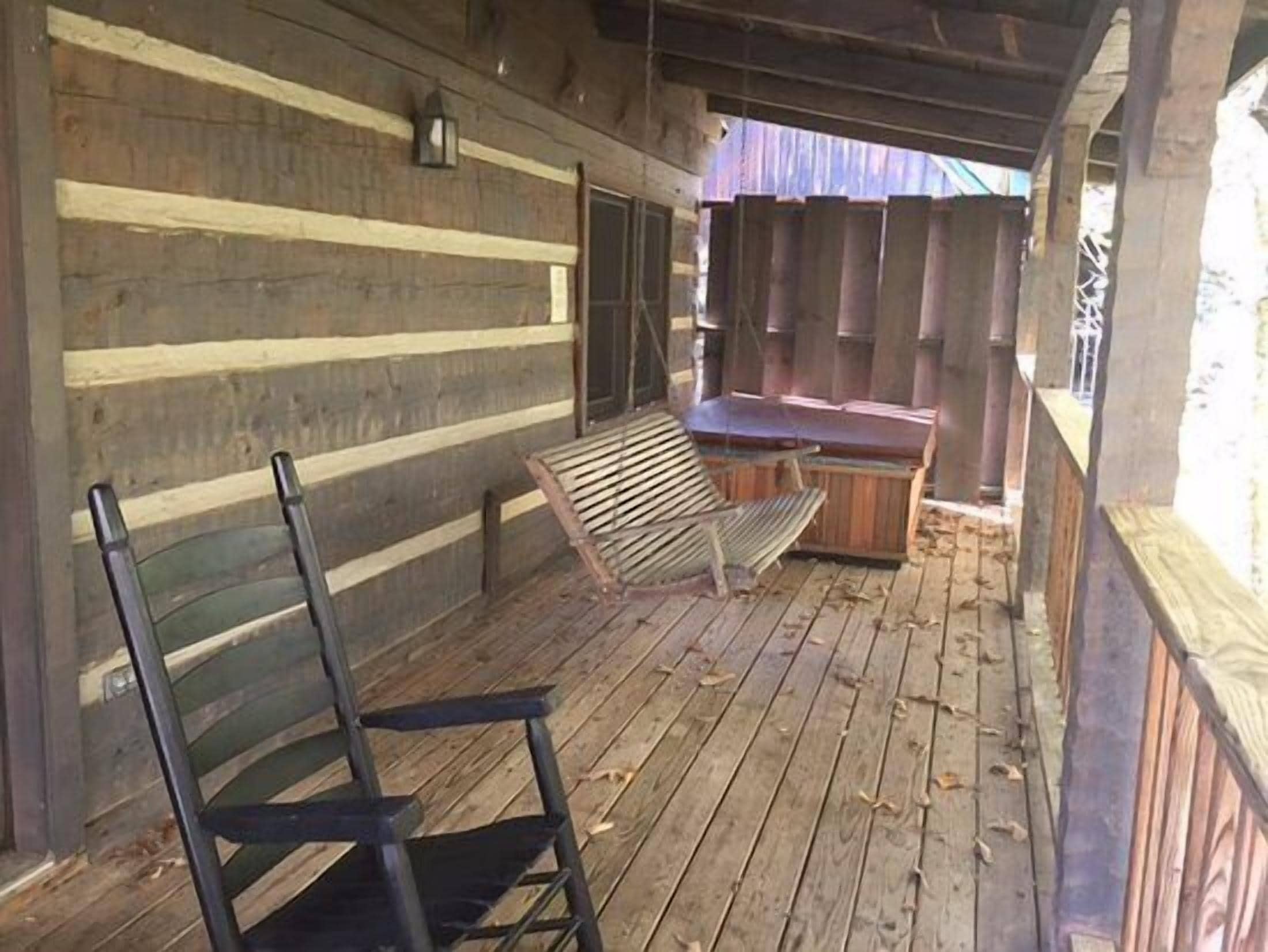 A rustic wooden cabin with a porch, a wooden bench, and a small table.