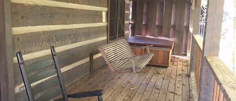 A rustic wooden cabin with a porch, a wooden bench, and a small table.