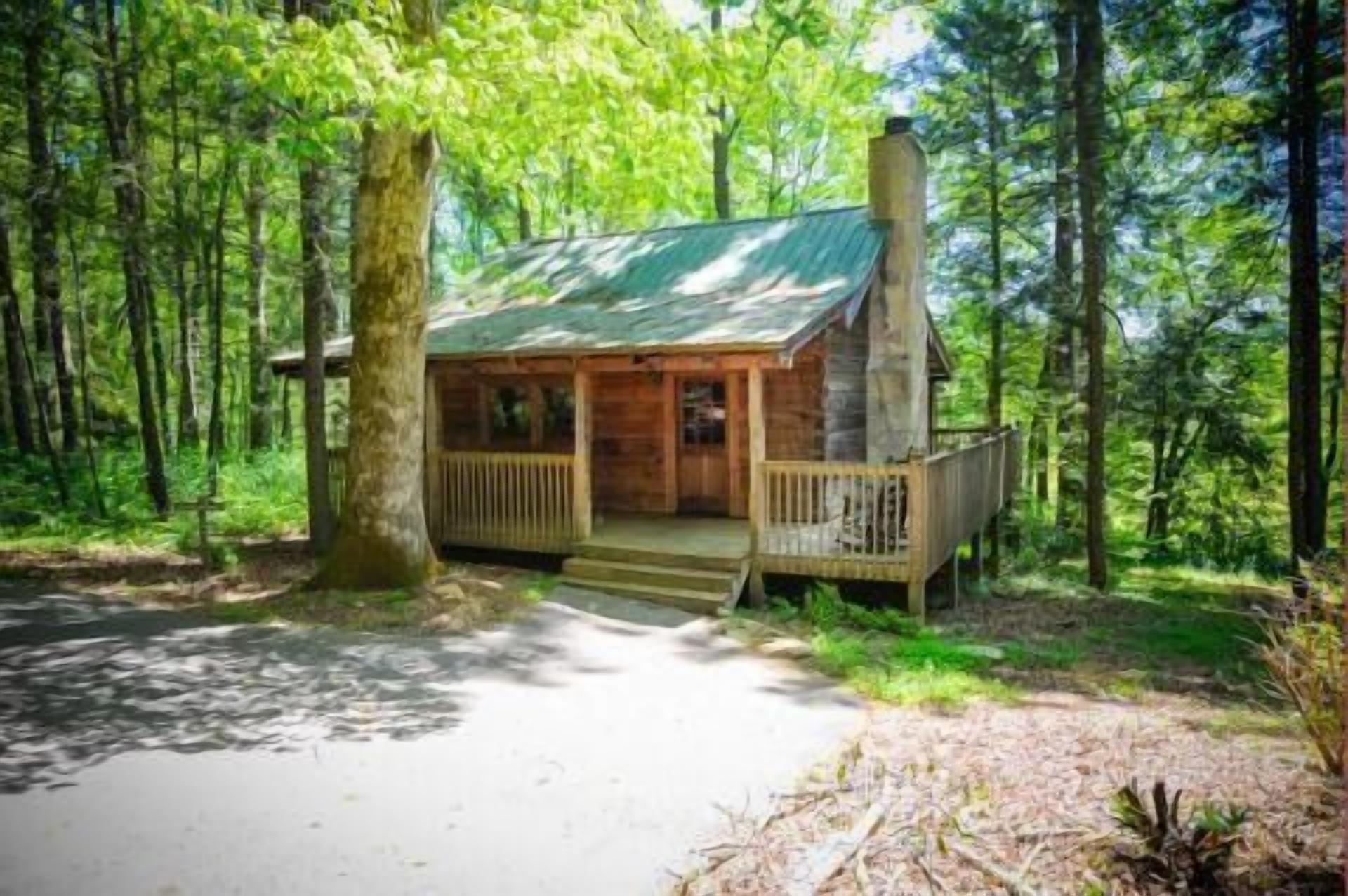A cabin with a porch and a chimney, surrounded by trees.