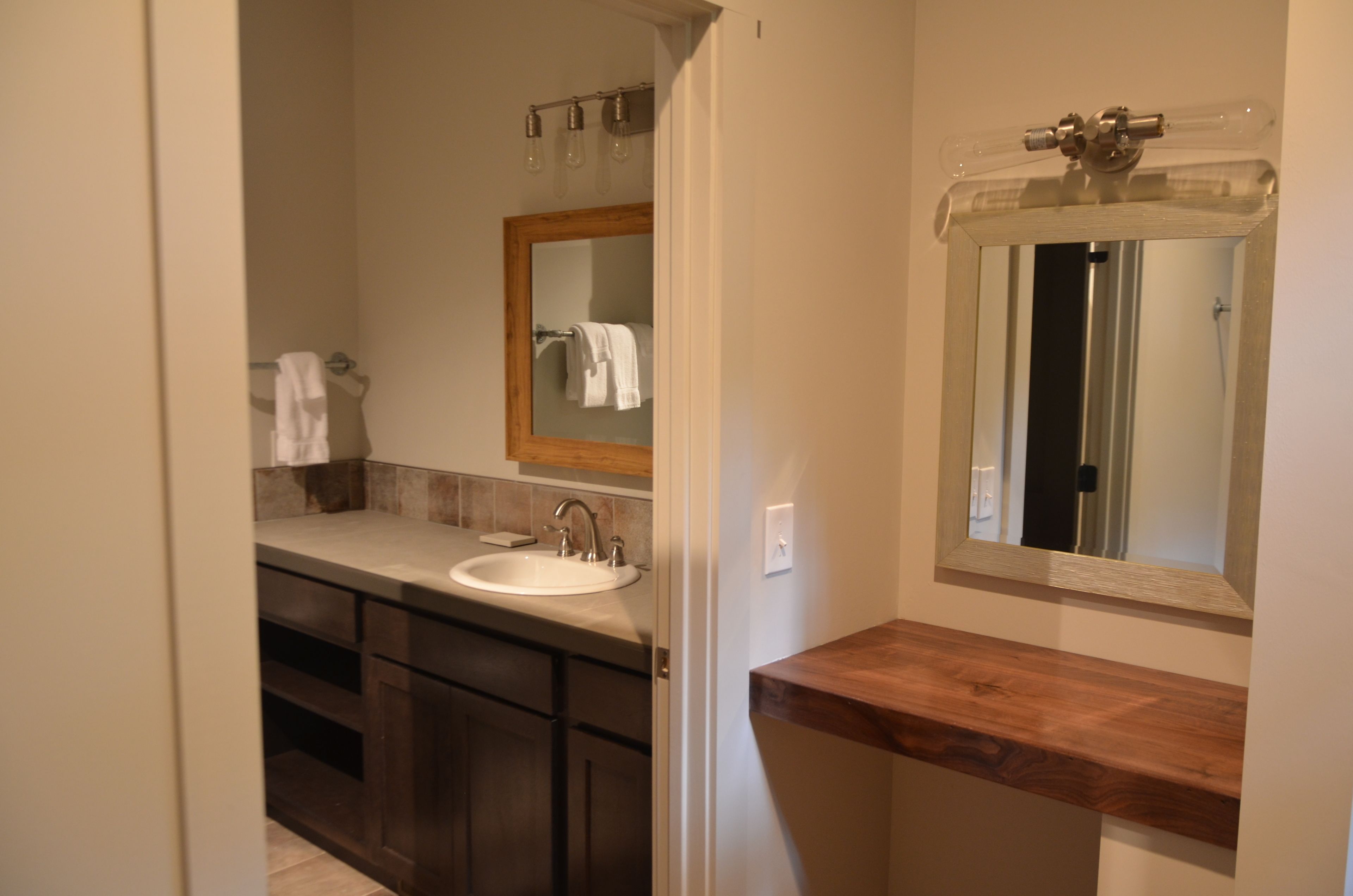 A bathroom with a wooden vanity, a sink, and a mirror.