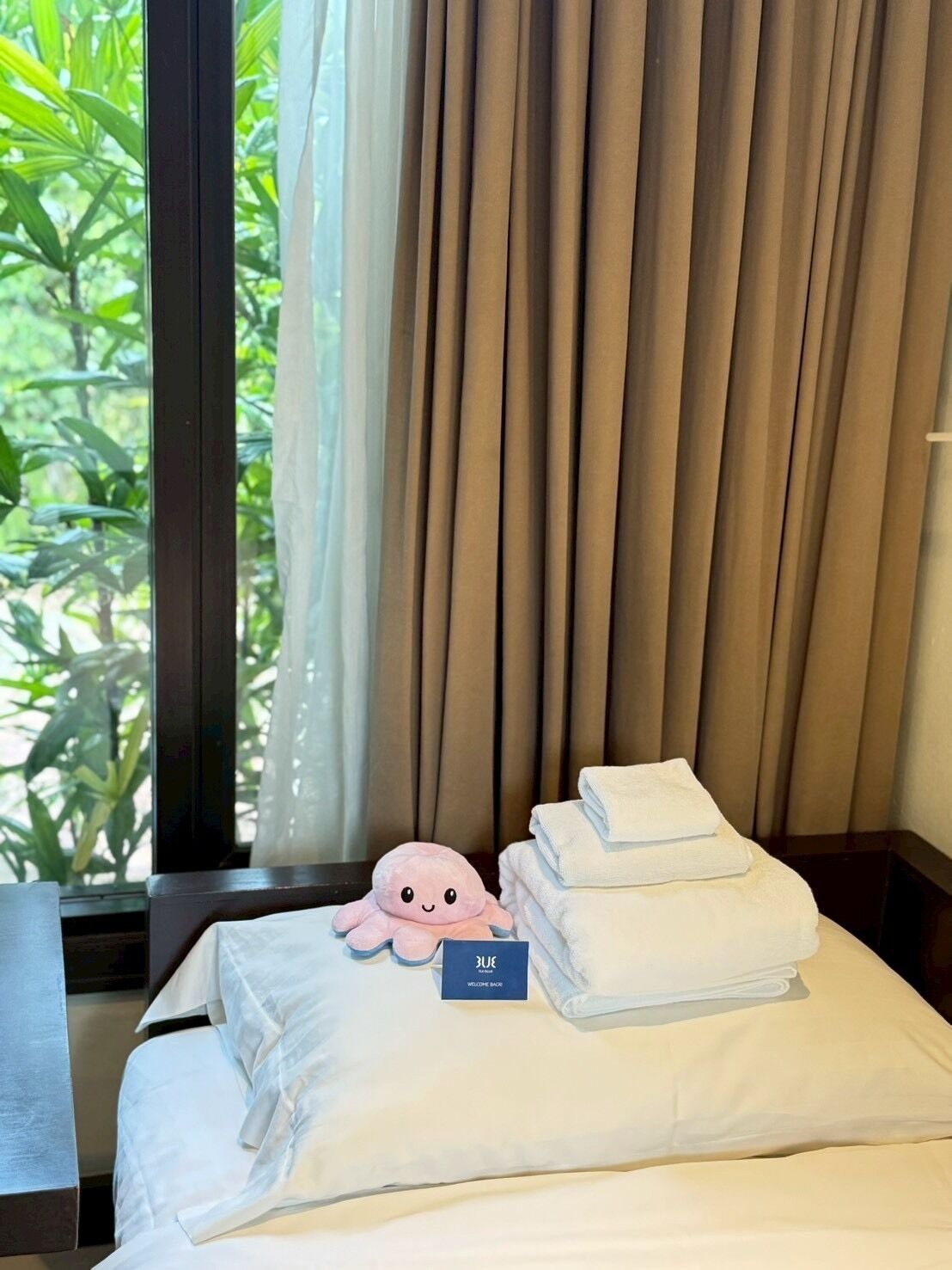 A hotel room with a bed, a plush octopus toy, and neatly folded towels.