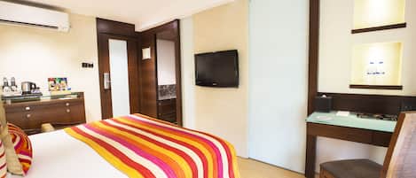 Une chambre d’hôtel équipée d’un lit, d’un bureau, d’une chaise, d’une télévision et d’un mini-bar.
